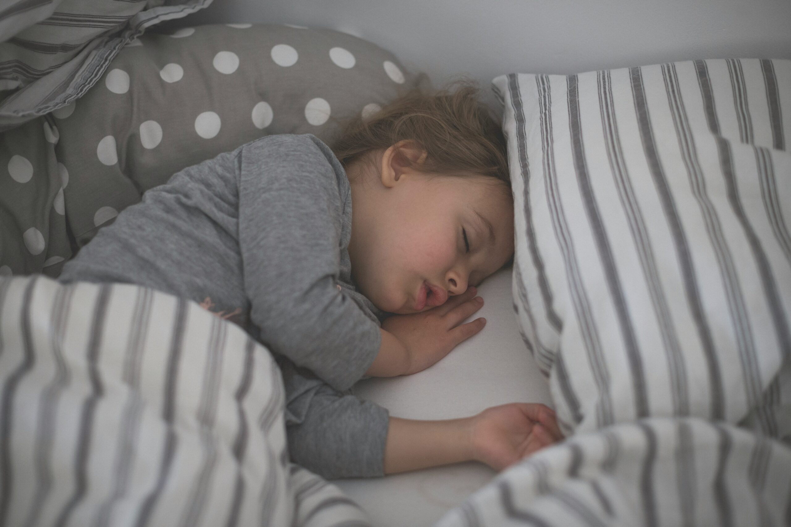 kind wuehlt vor dem einschlafen bett Foto von Isaac Quesada auf Unsplash